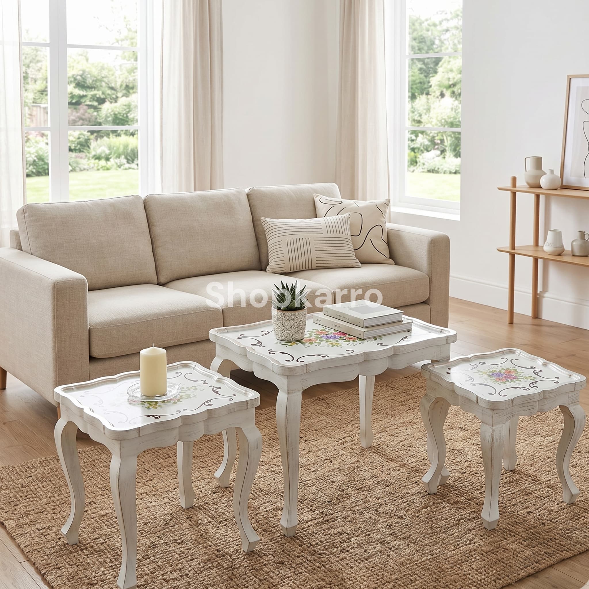 Overhead angled view of three white antique nesting tables nested together showing all three decorated tabletops