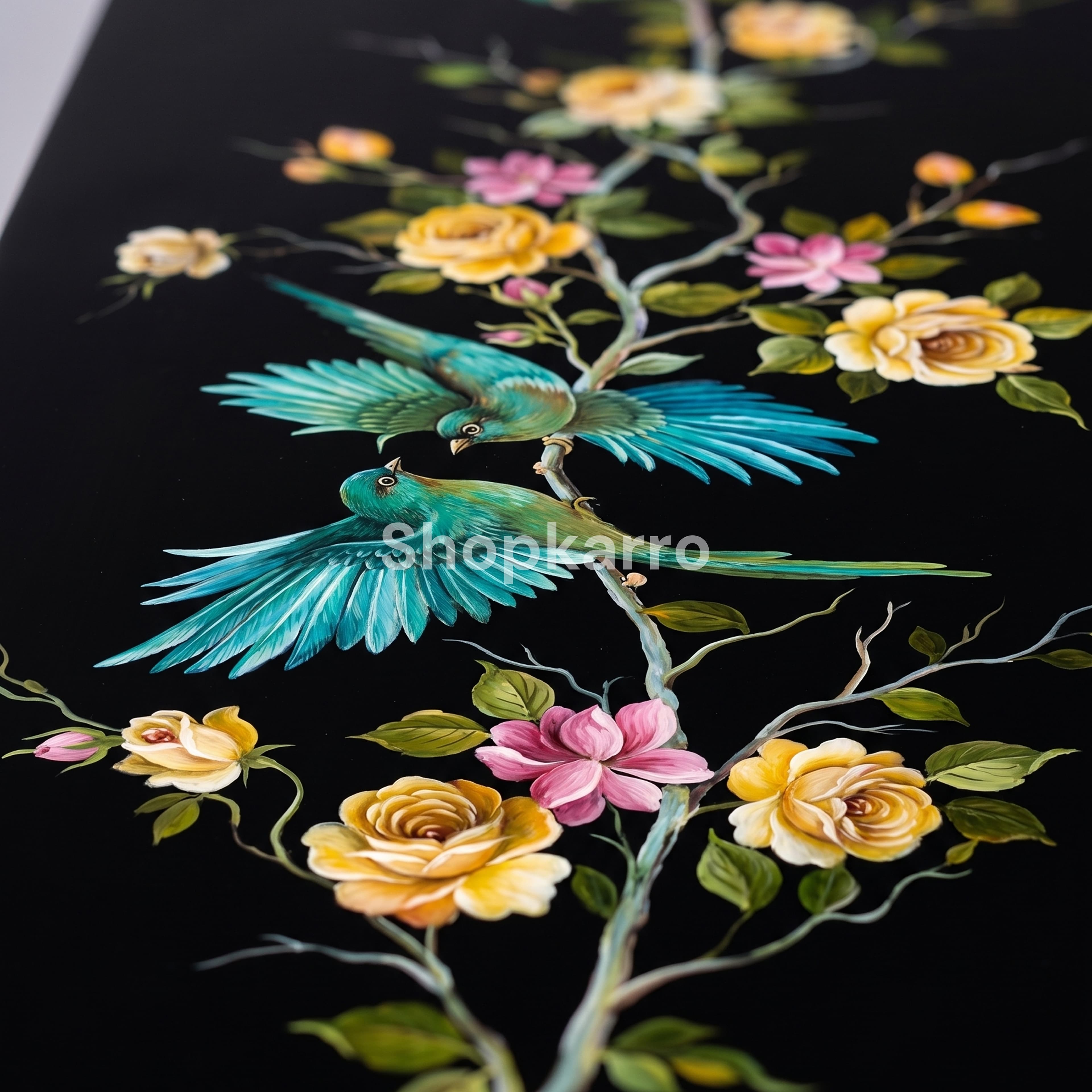 Close-up of hand-painted turquoise birds and blooming floral branches on black lacquered console tabletop